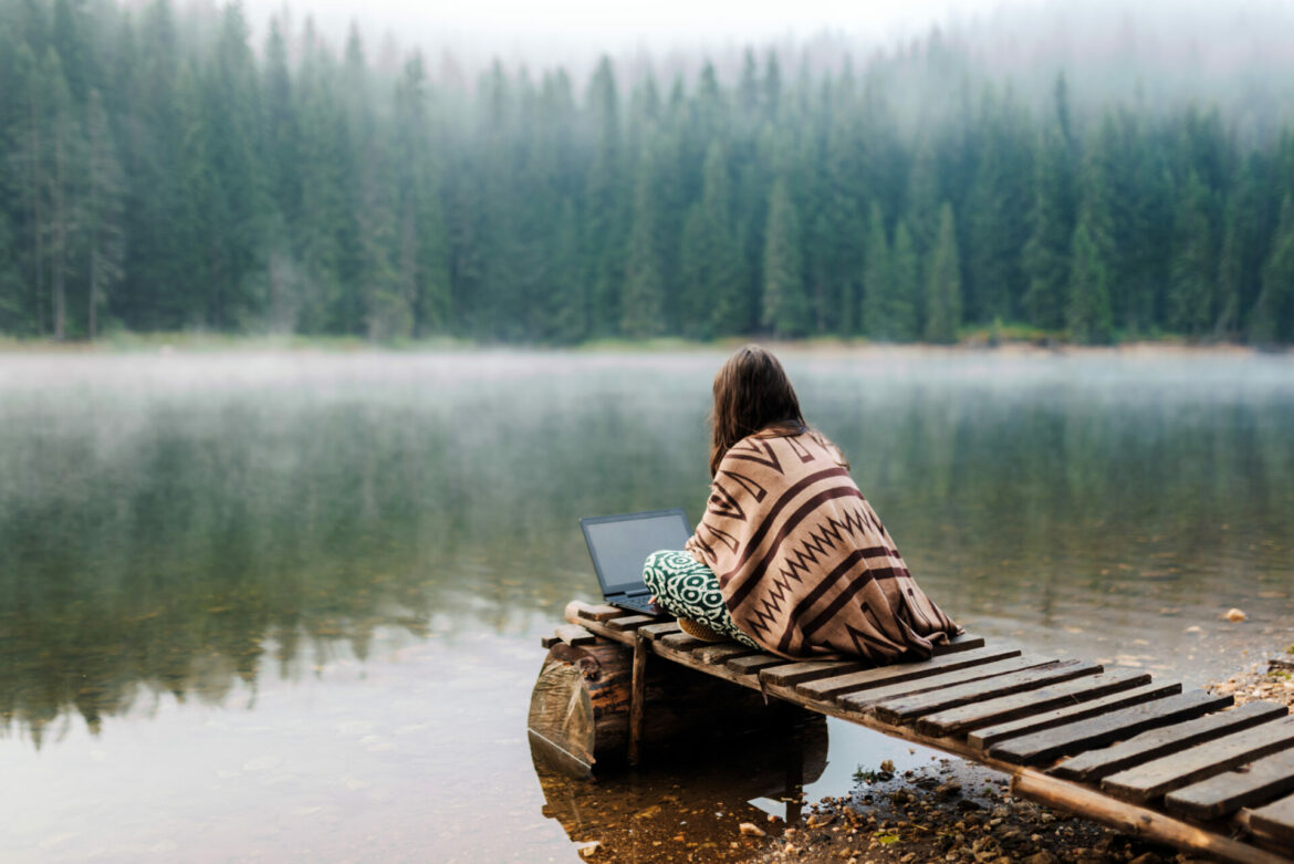 Woman Relaxing In Nature And Using Technology